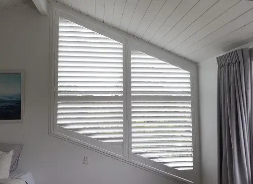 Shaped window plantation shutters fitted to an angled window
