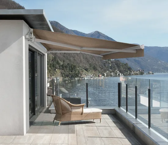 Modern retractable awning over lakeside balcony with glass balustrade and panoramic views